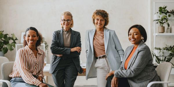 Four professional women posing confidently in a modern office space.