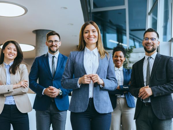 Confident business team standing together smiling in an office environment.