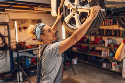 A professional auto technician carefully inspecting and working on a vehicle's tire.