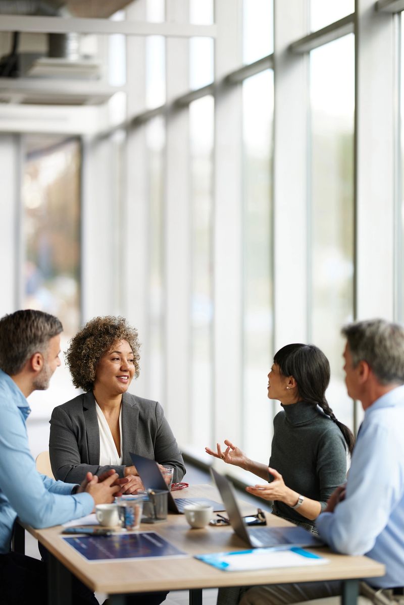 Happy multiracial entrepreneurs communicating while working on a meeting in the office. Focus is on woman with curly hair.