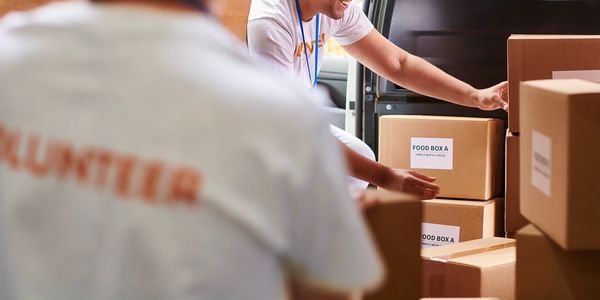 Volunteers loading labeled food boxes into a van for distribution.