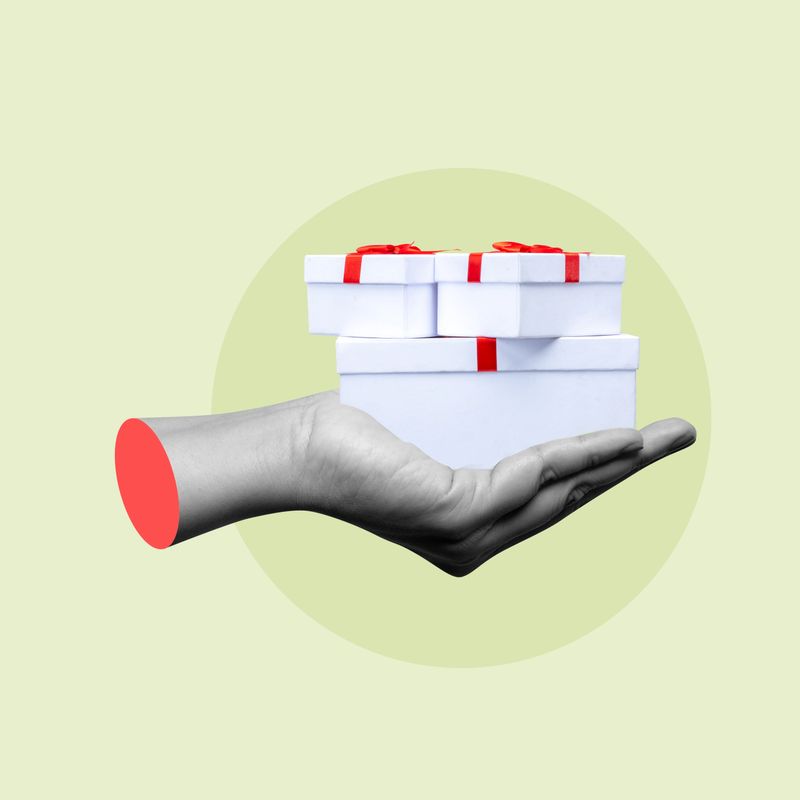 Hand is holding a stack of white gift boxes with red ribbons, symbolizing giving and receiving presents for special occasions