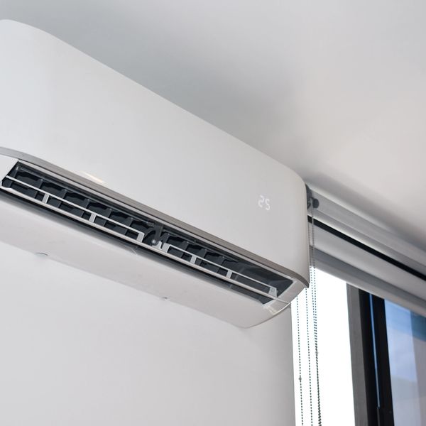 Modern white wall-mounted air conditioner with digital display set at 25°C.
