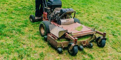 Person mowing grass with a large mower.