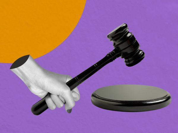 A hand holding a judge's gavel and sound block.