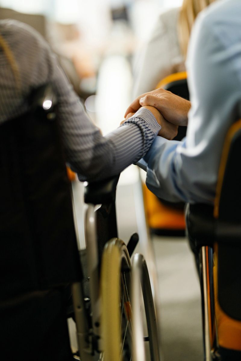Close up of unrecognizable business couple holding hands during a seminar in board room. Woman is in a wheelchair.