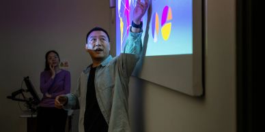 男士用激光笔指向投影仪上的图表演示。