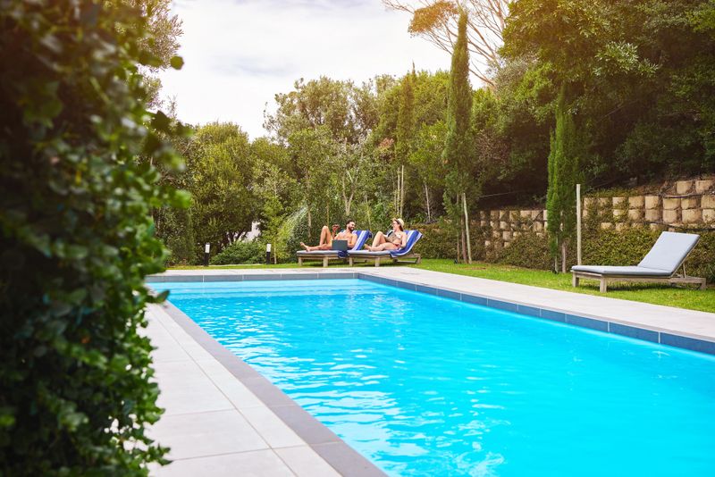 Swimming pool, people and chairs outdoor for relax, travel and summer at luxury hotel as holiday. Water, couple and sun loungers for wellness, hospitality and vacation at resort with freedom