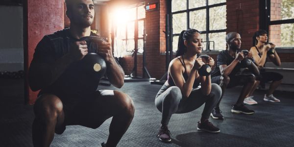 Group workout with kettlebells in a gym during sunset.