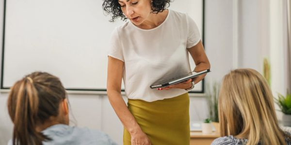 Teacher using tablet to assist students in classroom.
