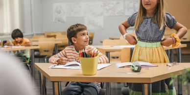 A boy and girl interacting in a classroom setting.