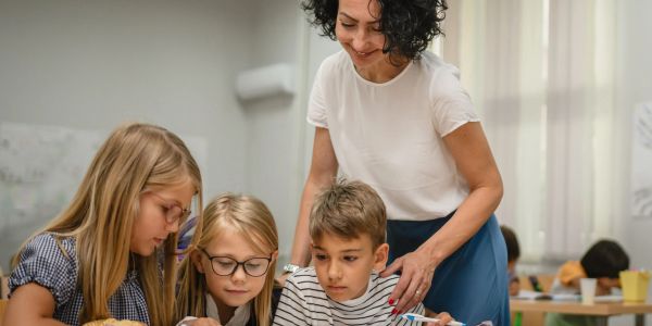 Teacher helping children with their work in a classroom.