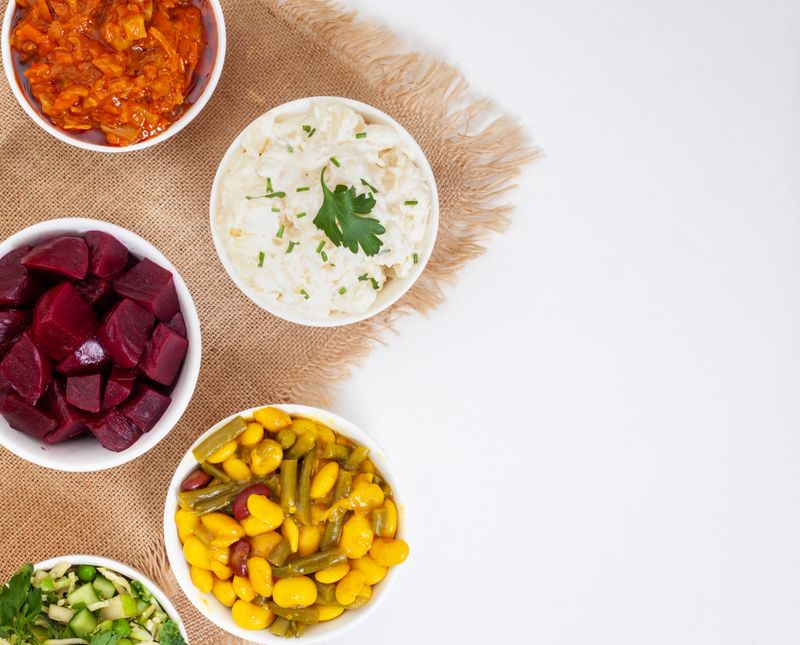 Traditional side dishes and salads for a perfect South African braai. Salads on white with Burlap cloth and copy space