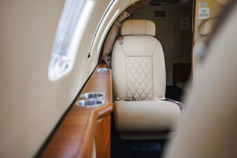 Close-up view of a luxurious private jet's interior, highlighting the plush leather seating and polished wood finish.