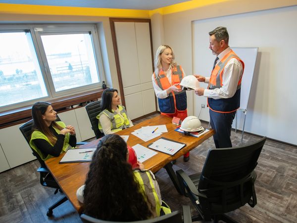 Construction team meeting in an office, discussing safety helmets.