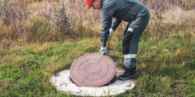 Man looking into sewage tank.