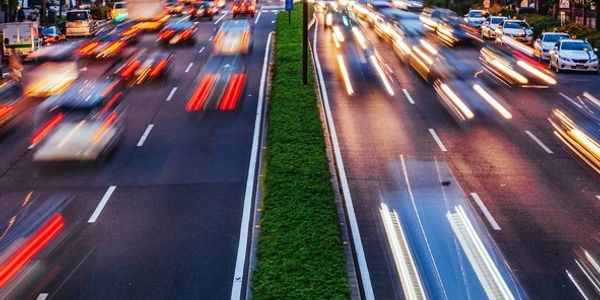 City highway at dusk with light trails from fast-moving vehicles.