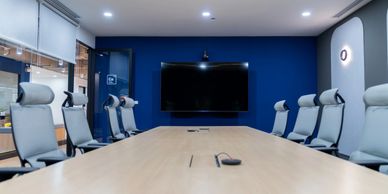 Modern conference room with ergonomic chairs and a large screen on a blue wall.