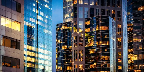 Modern office buildings with illuminated windows at dusk.