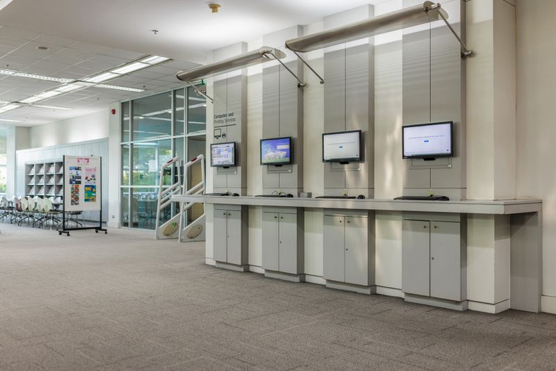 Interior view of a modern Bangkok university library. Computers on the wall for students to use.