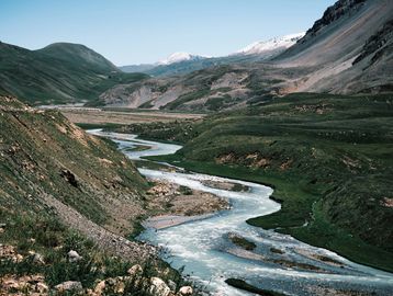 A winding river through lush green mountains under a clear blue sky.