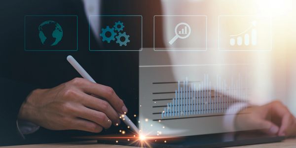 Person using digital pen on tablet with business icons and charts overlay.