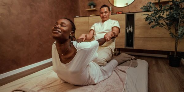 A woman receiving a relaxing back stretch from a massage therapist.