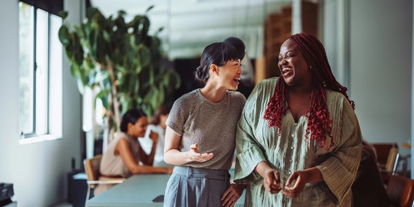 Two women laughing and enjoying a conversation indoors.