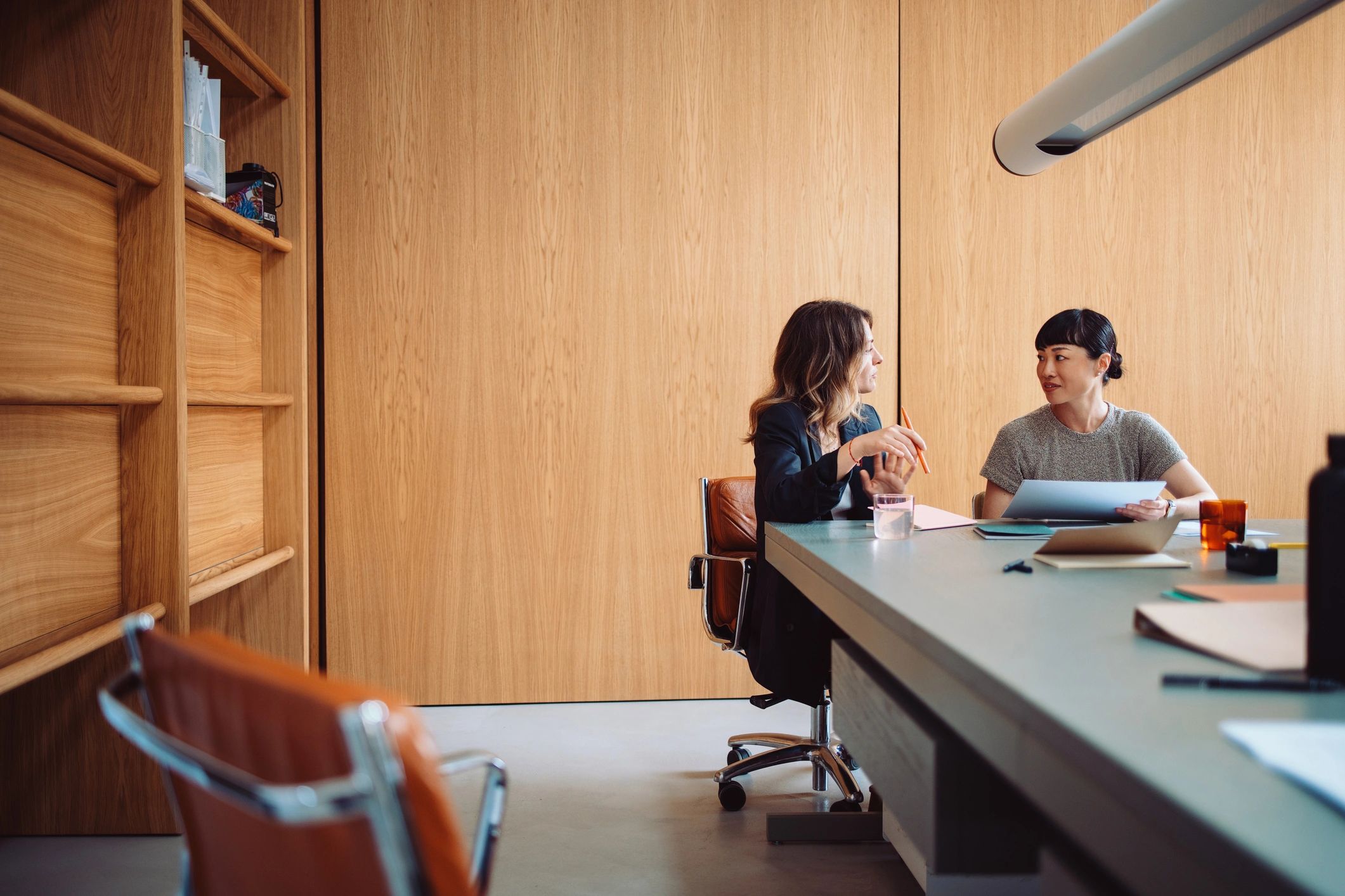 Two women having a discussion in a wooden office.