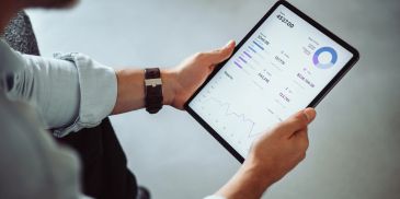 Person holding tablet showing financial data.