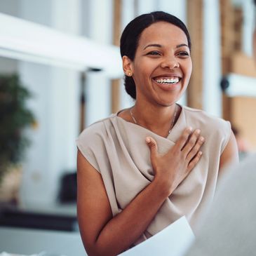 Professionally dressed woman with hand on heart as if to say thank you