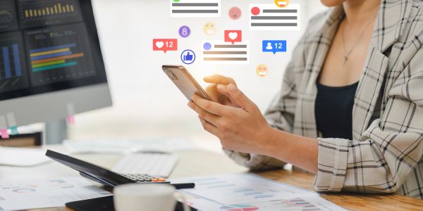 Person engaging with social media notifications on a smartphone at a work desk.