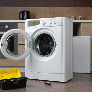 Washing machine with an open door and toolkit.