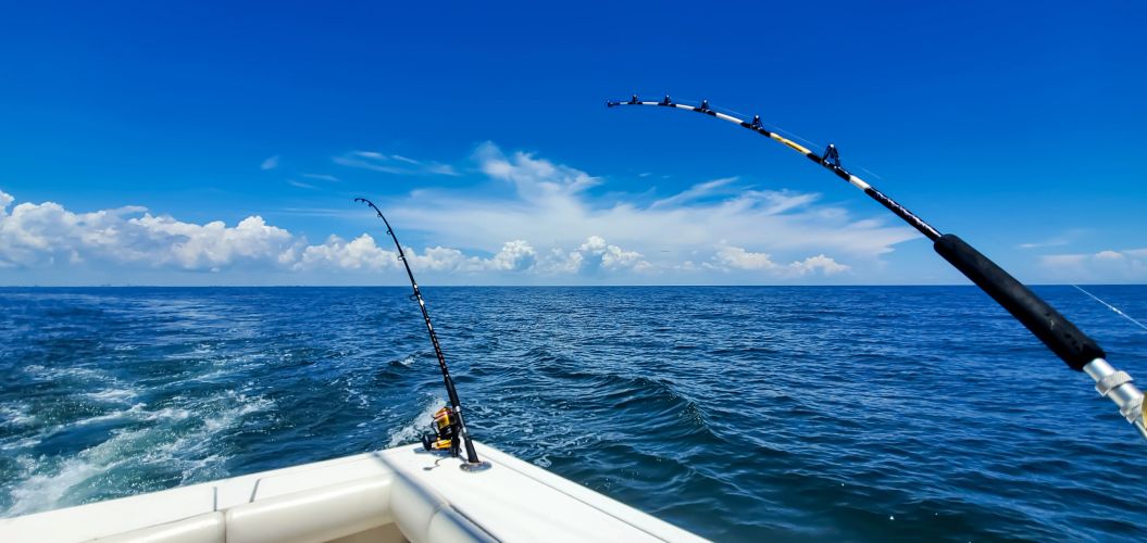 Fishing rods bending on a boat in the ocean on a sunny day.