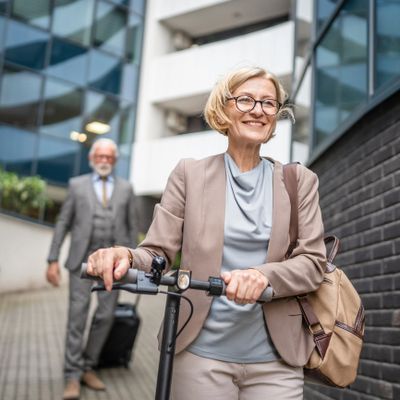 Smiling woman rides an electric scooter in an urban setting.