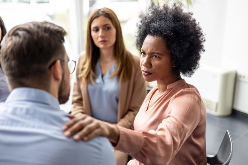 Captured in close-up, a worried psychologist converses seriously with colleagues in an office setting