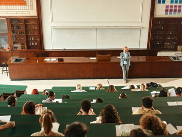 Professor lecturing in a large, old-fashioned classroom.