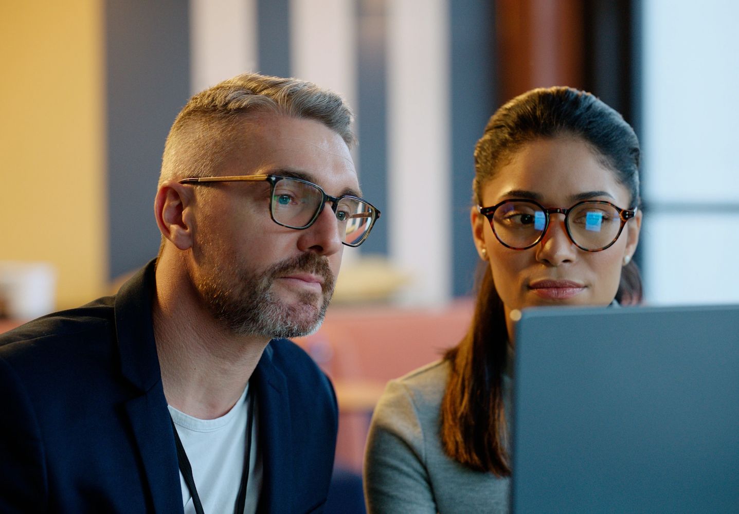 Two professionals reviewing information together on a laptop.
