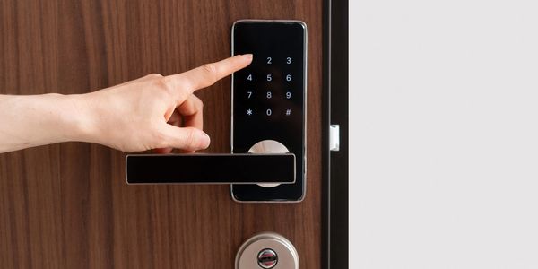 Hand pressing a number on a digital door lock keypad.