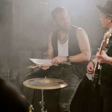 Two musicians rehearsing with instruments and sheet music in a smoky room.