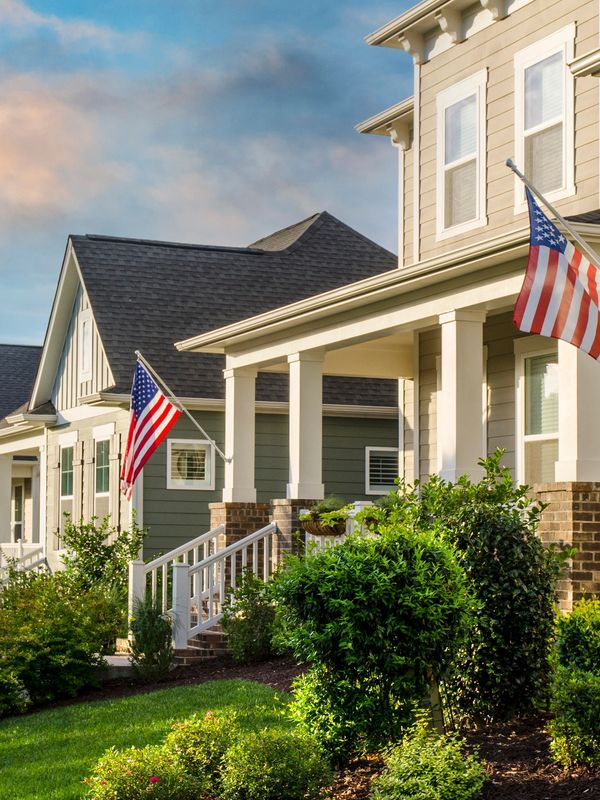 Row of suburban homes with American flags and well-kept gardens.