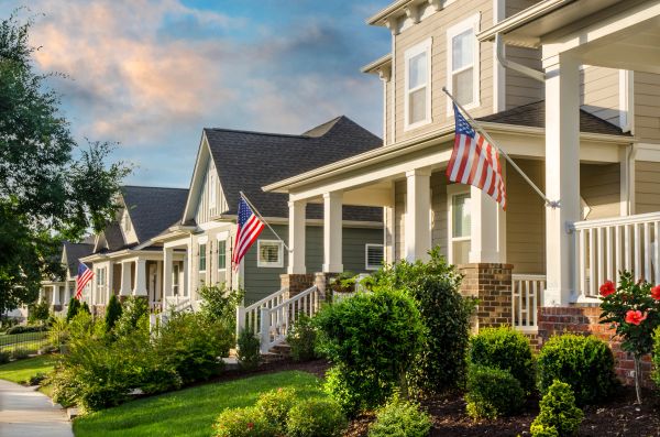 Row of suburban homes with American flags and well-kept gardens.