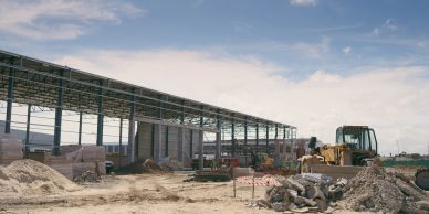 Construction site with heavy machinery and building materials under a blue sky.