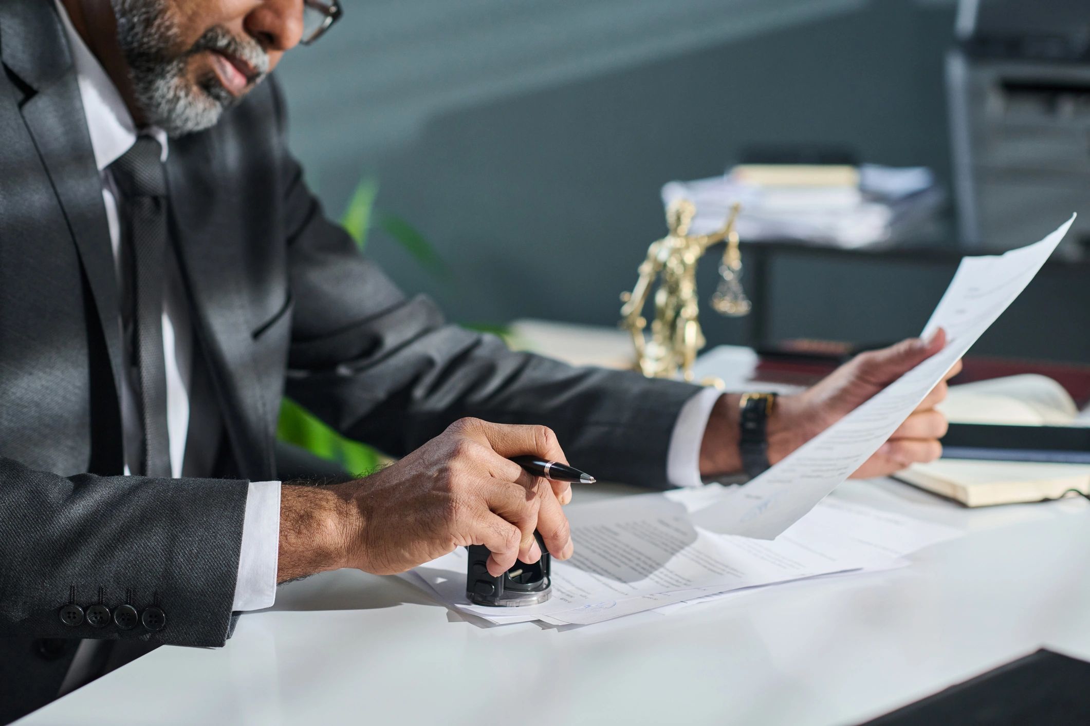 Lawyer stamping and reviewing legal documents at desk.