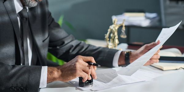 A man in a suit stamping documents at a desk.