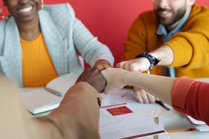 Close-up shot of hands of multi-ethnic business team giving fist bump during office meeting, showing unity and collaboration