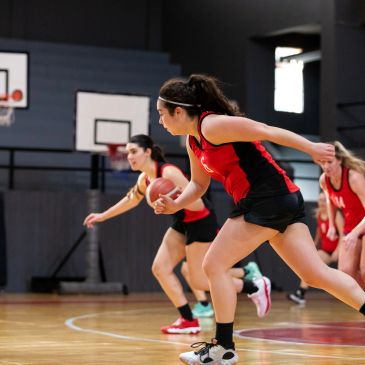 Women playing basketball on an indoor court.