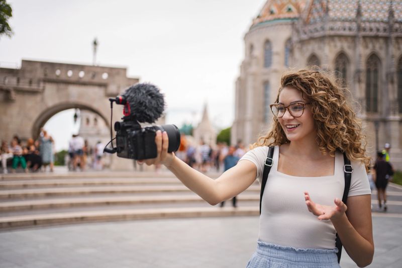 A young woman records her travel adventures in Budapest, excitedly sharing her experiences at the iconic Fisherman's Bastion.