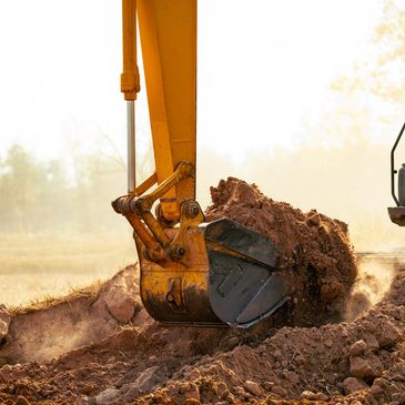 Yellow excavator digging soil at a construction site.