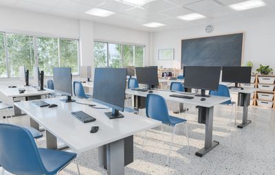 Empty modern classroom with computers and blue chairs.